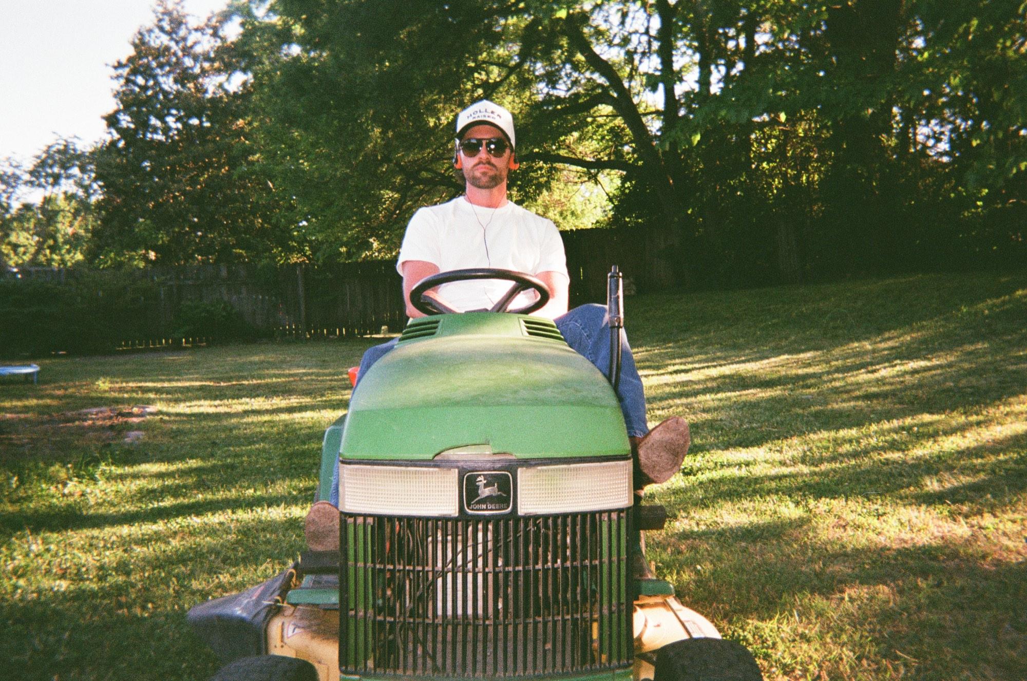 Will Jones on a tractor in a shaded backyard